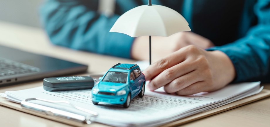 Mężczyzna podpisuje obowiązkowe ubezpieczenie OC samochodu.