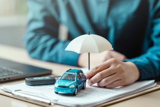 Mężczyzna podpisuje obowiązkowe OC samochodu.