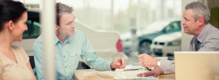Trzy osoby w trakcie podpisywania umowy kupna-sprzedaży samochodu
