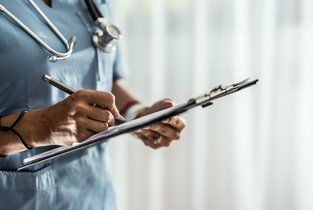 Lekarz uzupełniający dokumentację jest w trakcie badania lekarskiego na prawo jazdy kat. B.